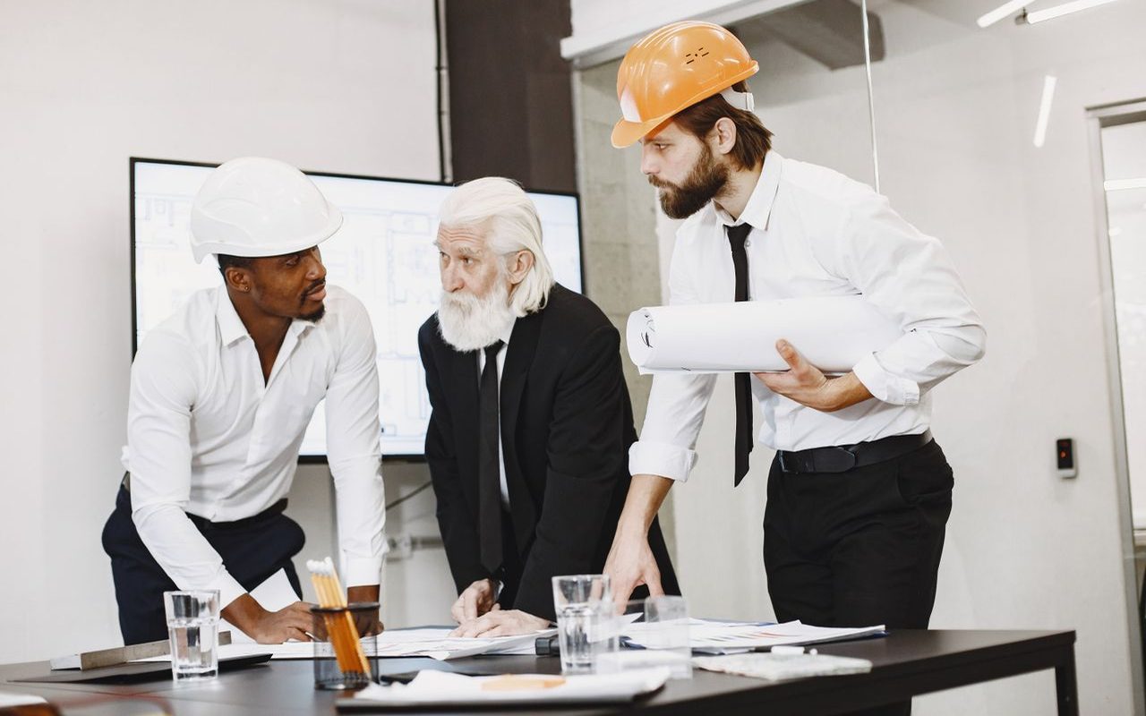 Professionals mentoring a young adult around a table in a bright upper-floor office