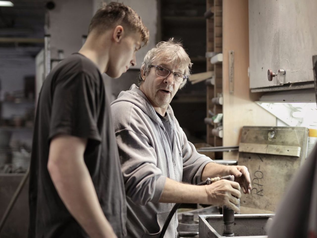 A mentor guiding an apprentice's hands through a hands-on task
